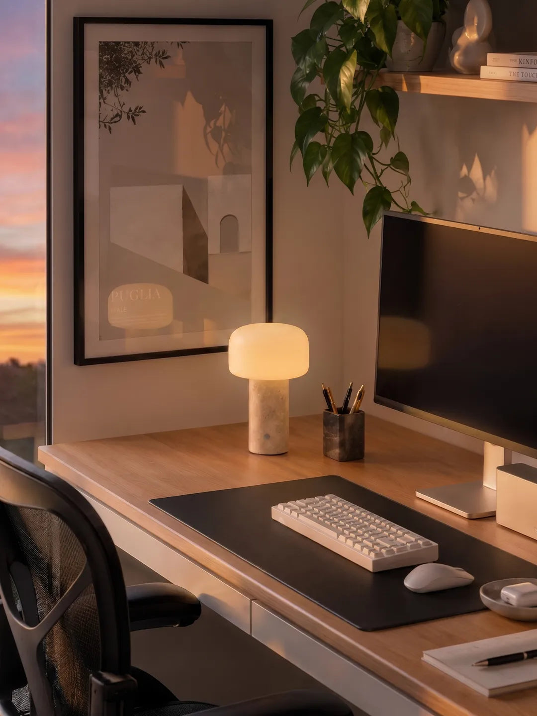 Hooled Vesper Stone Tischleuchte auf einem Schreibtisch mit Monitor, Tastatur und Pflanzen