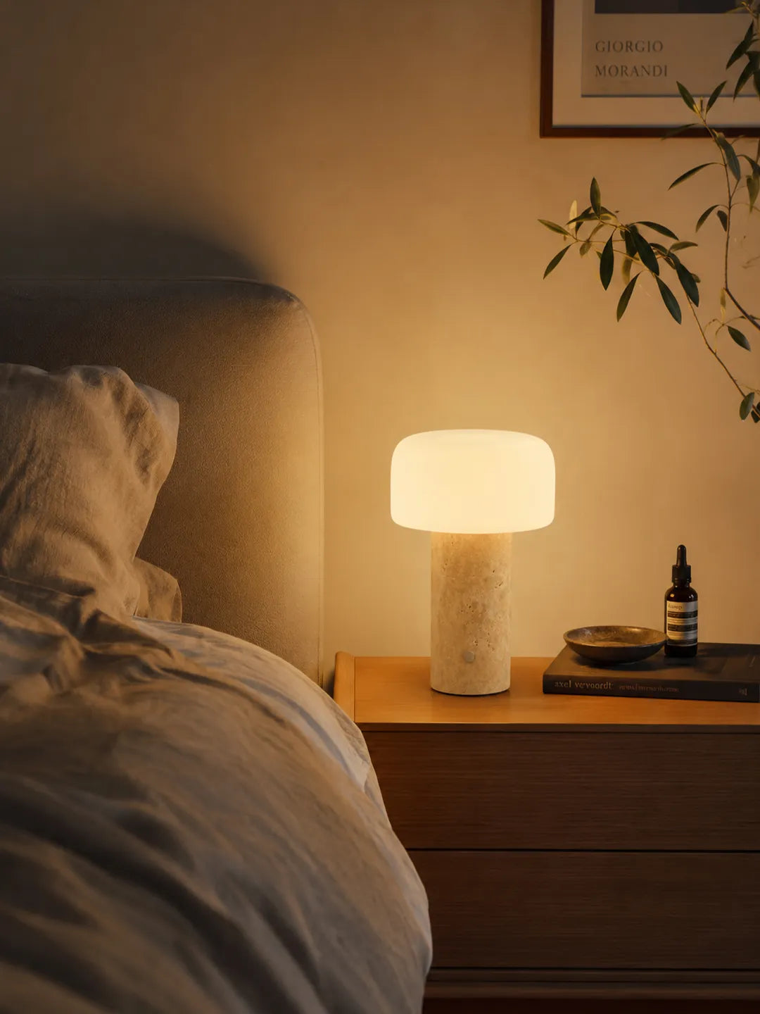 Hooled Vesper Stone Tischleuchte mit warmem Licht auf einem Nachttisch neben dem Bett